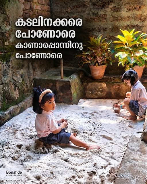 Two girls playing in a sandpit beside an old laterite wall